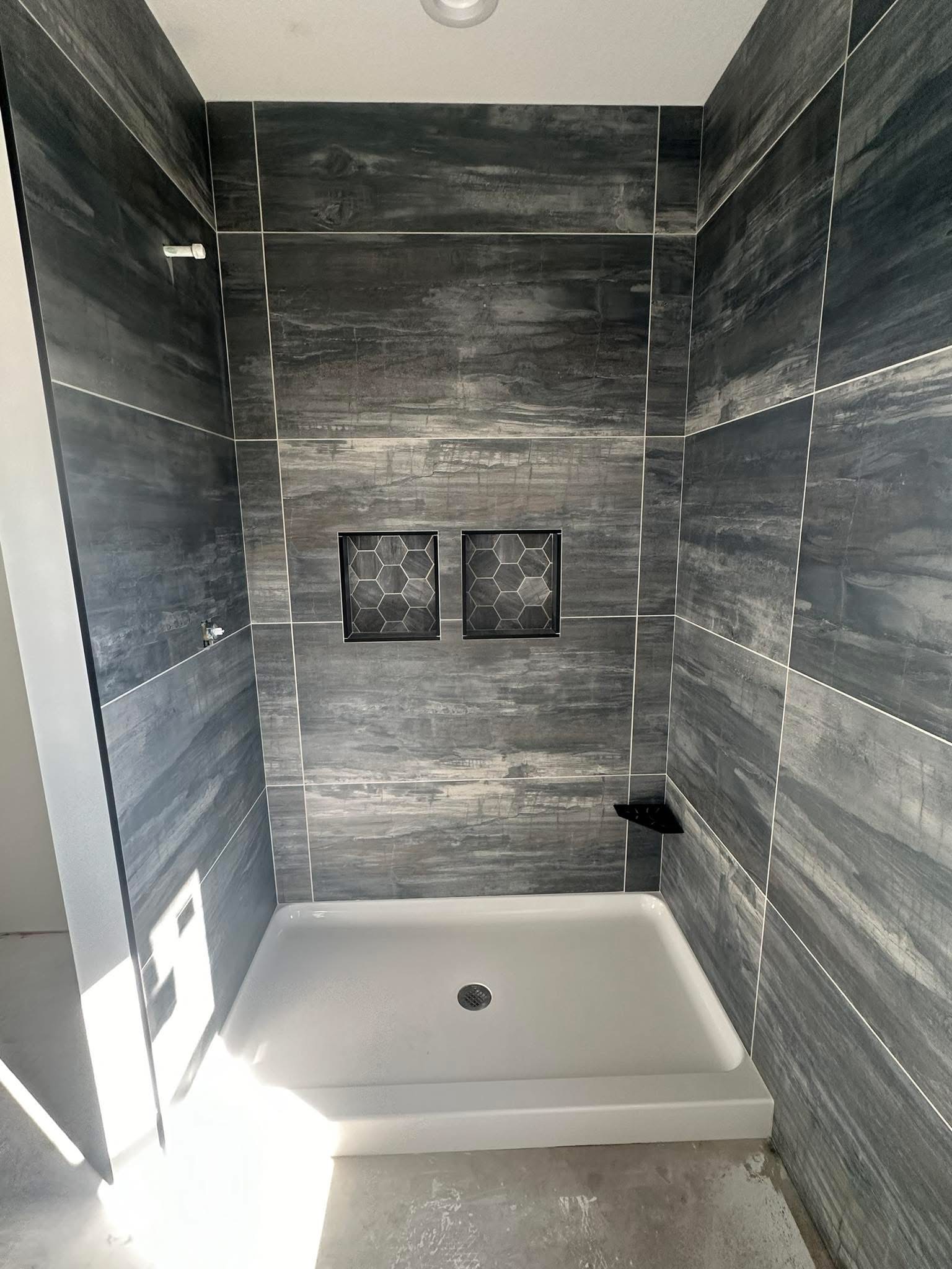 Dark stone-look shower walls with two hexagon-backed niches and a corner shelf.